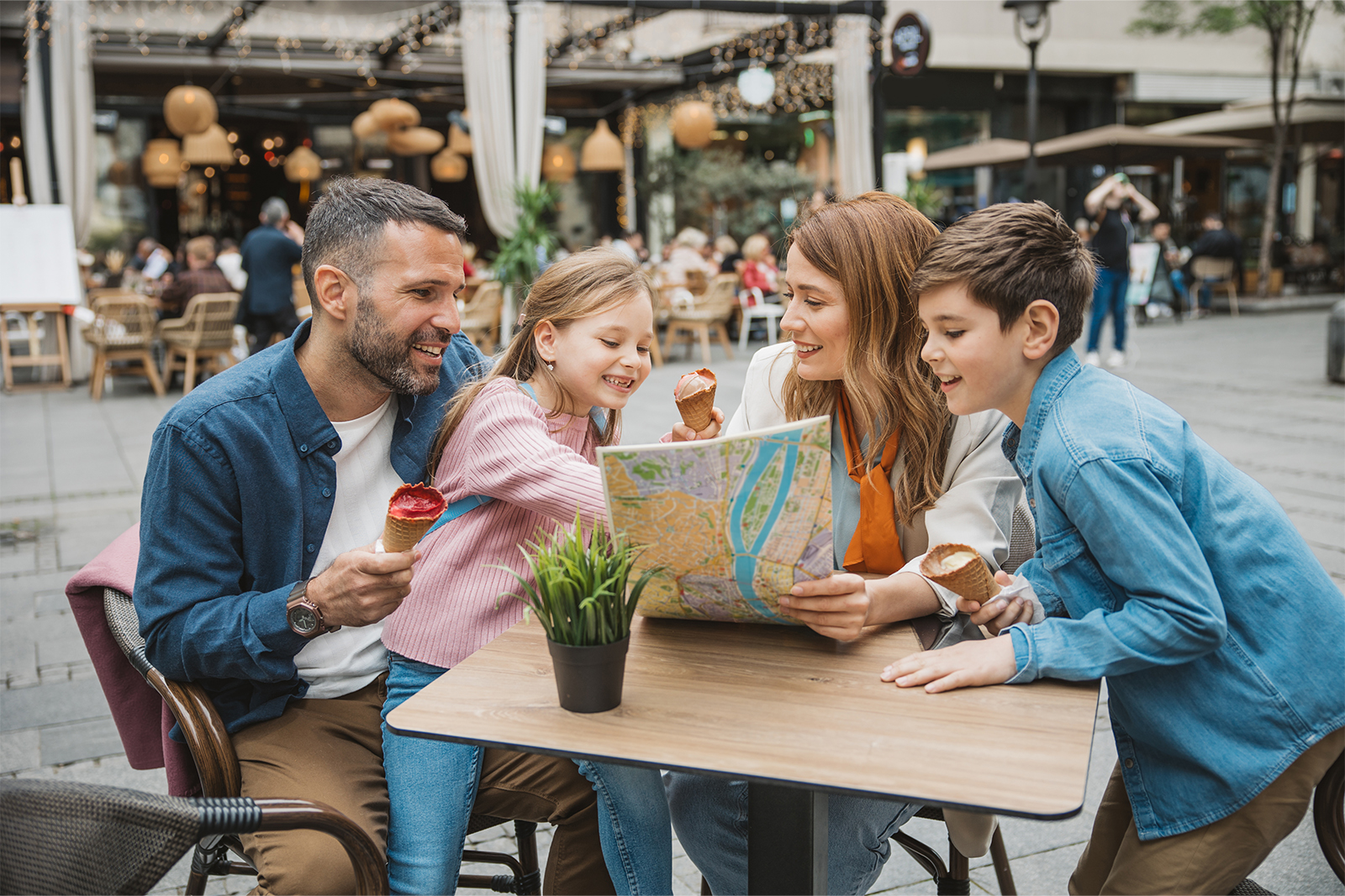 Happy young family on vacation. Parents and kids exploring European city, eating ice cream and looking map for direction.